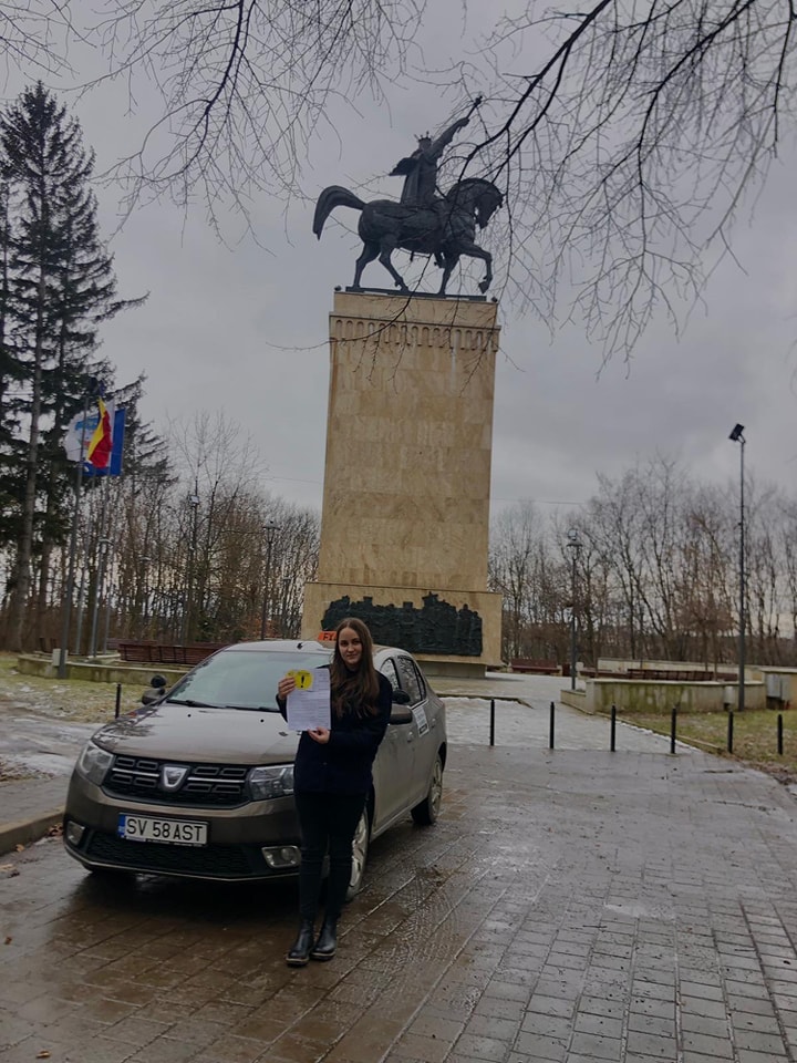 Absolvent AutoStar Drive lângă mașina de școală după examen
