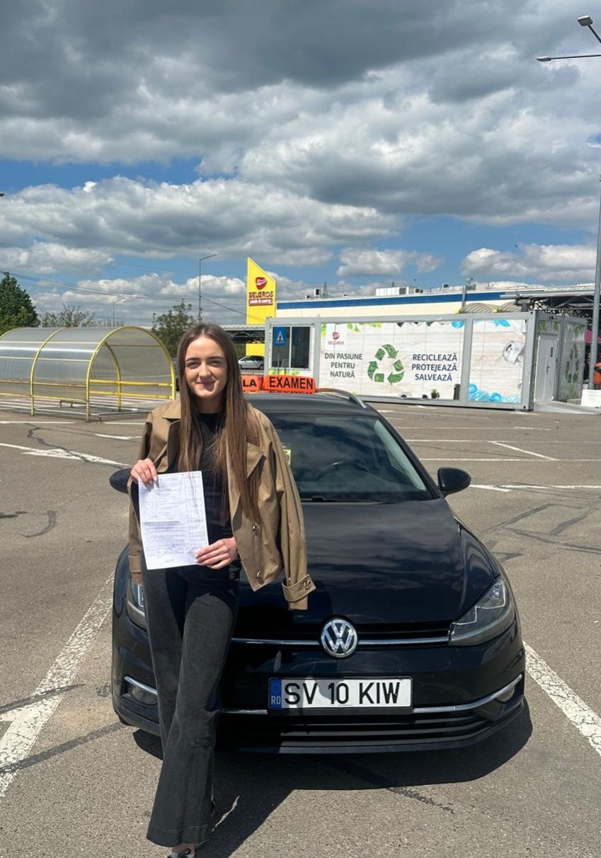 Absolventă AutoStar Drive lângă mașina de școală după examen
