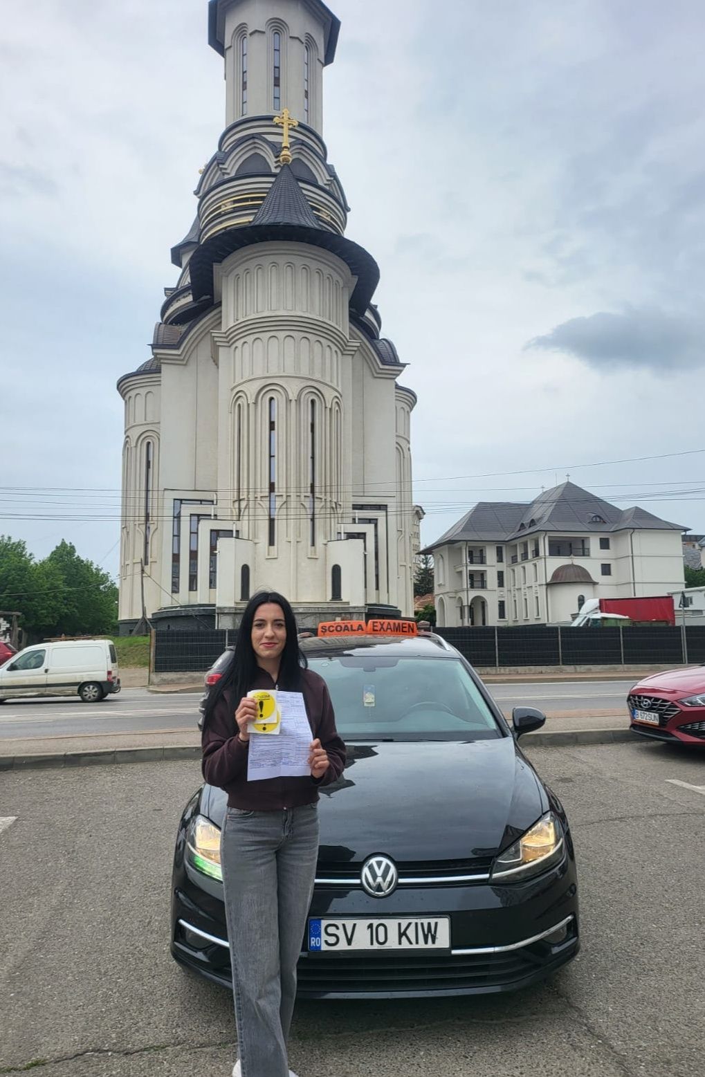 Absolventă AutoStar Drive lângă mașina de școală după examen