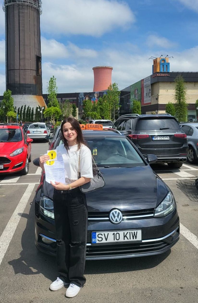Absolventă AutoStar Drive lângă mașina de școală după obținerea permisului