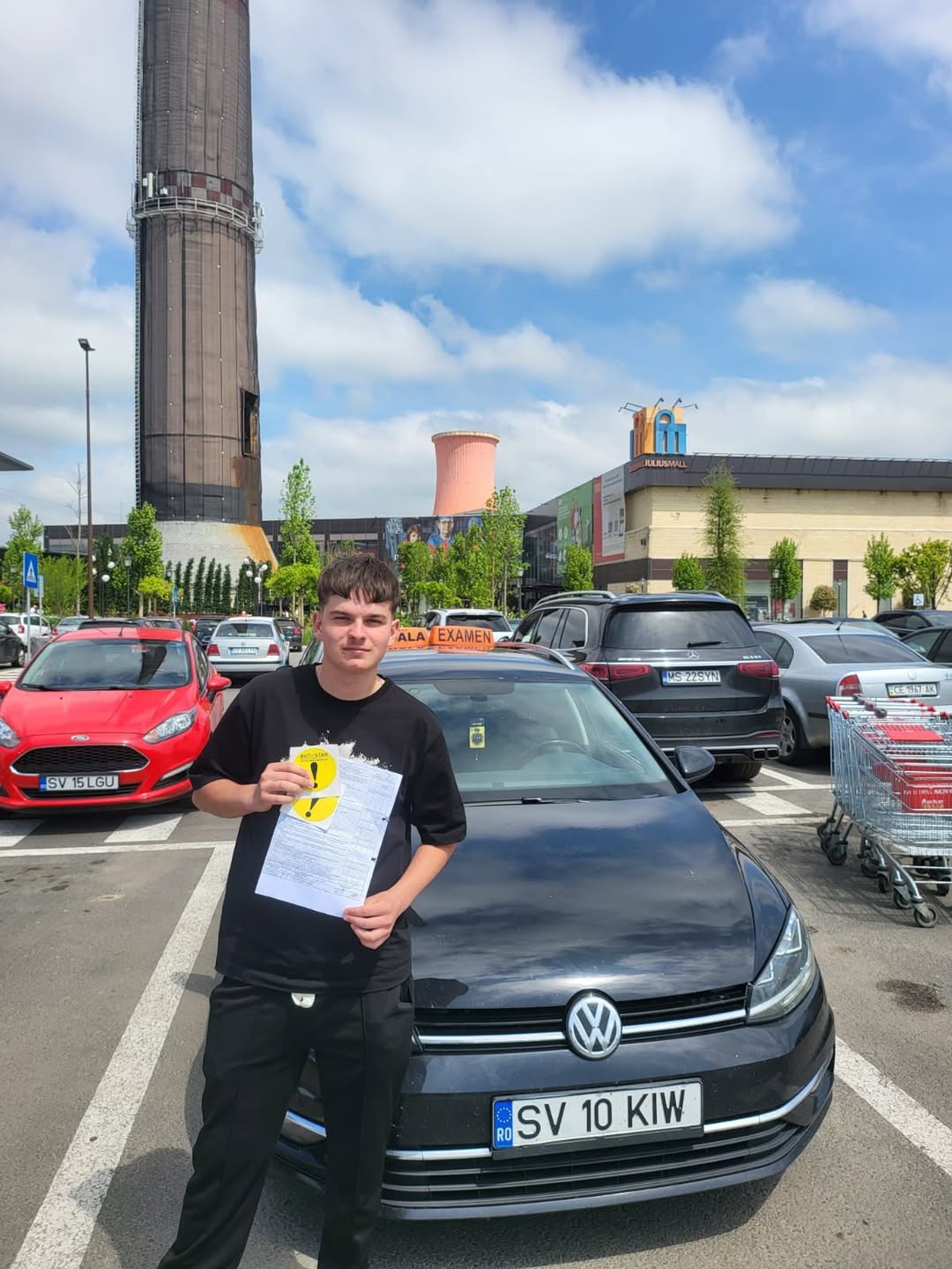 Absolvent AutoStar Drive lângă mașina de școală după examen