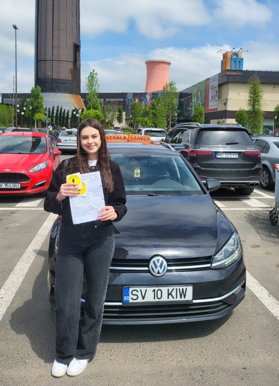 Absolventă AutoStar Drive cu permisul, lângă mașina de școală