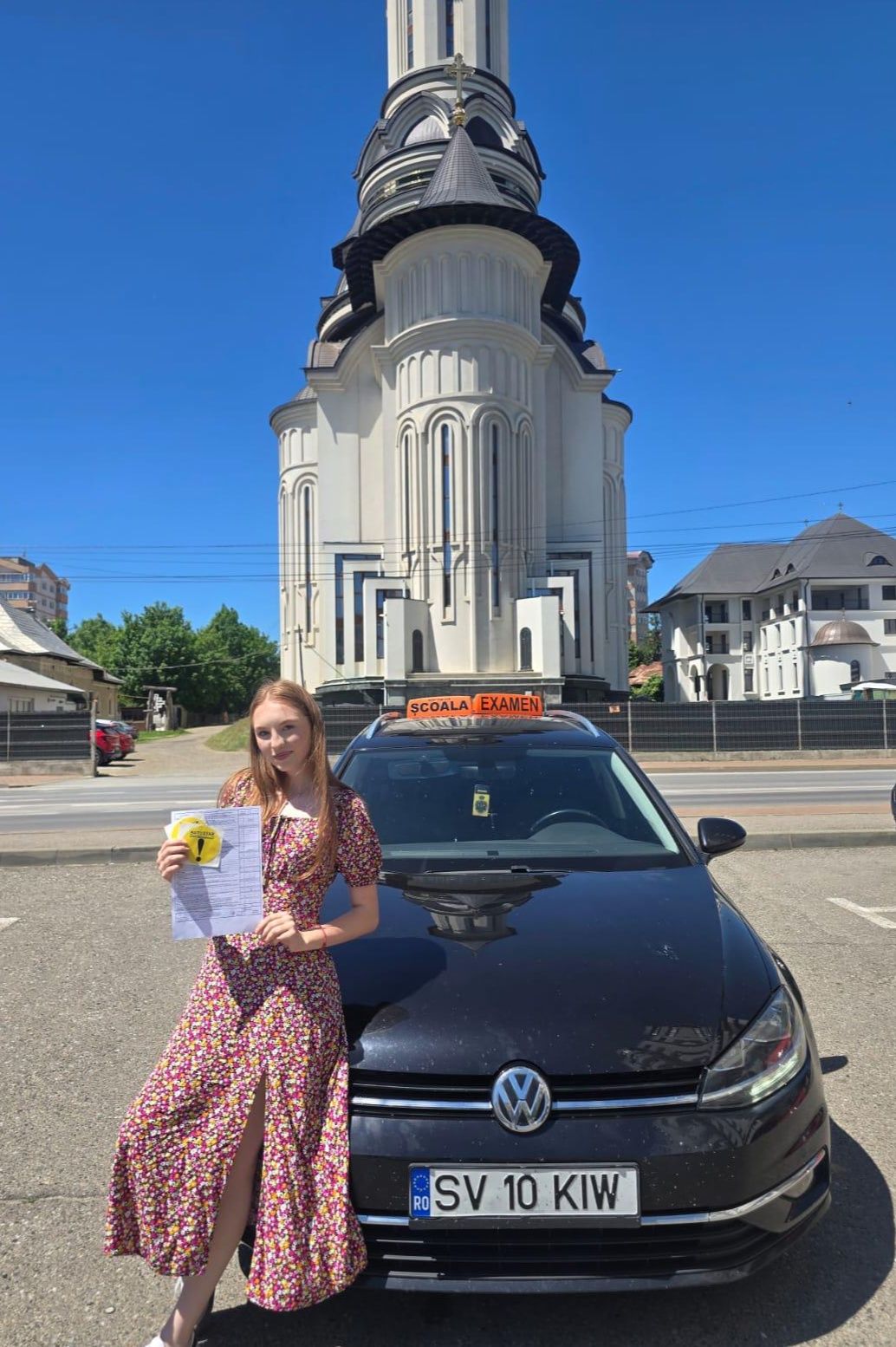 Absolventă AutoStar Drive lângă mașina de școală după examen