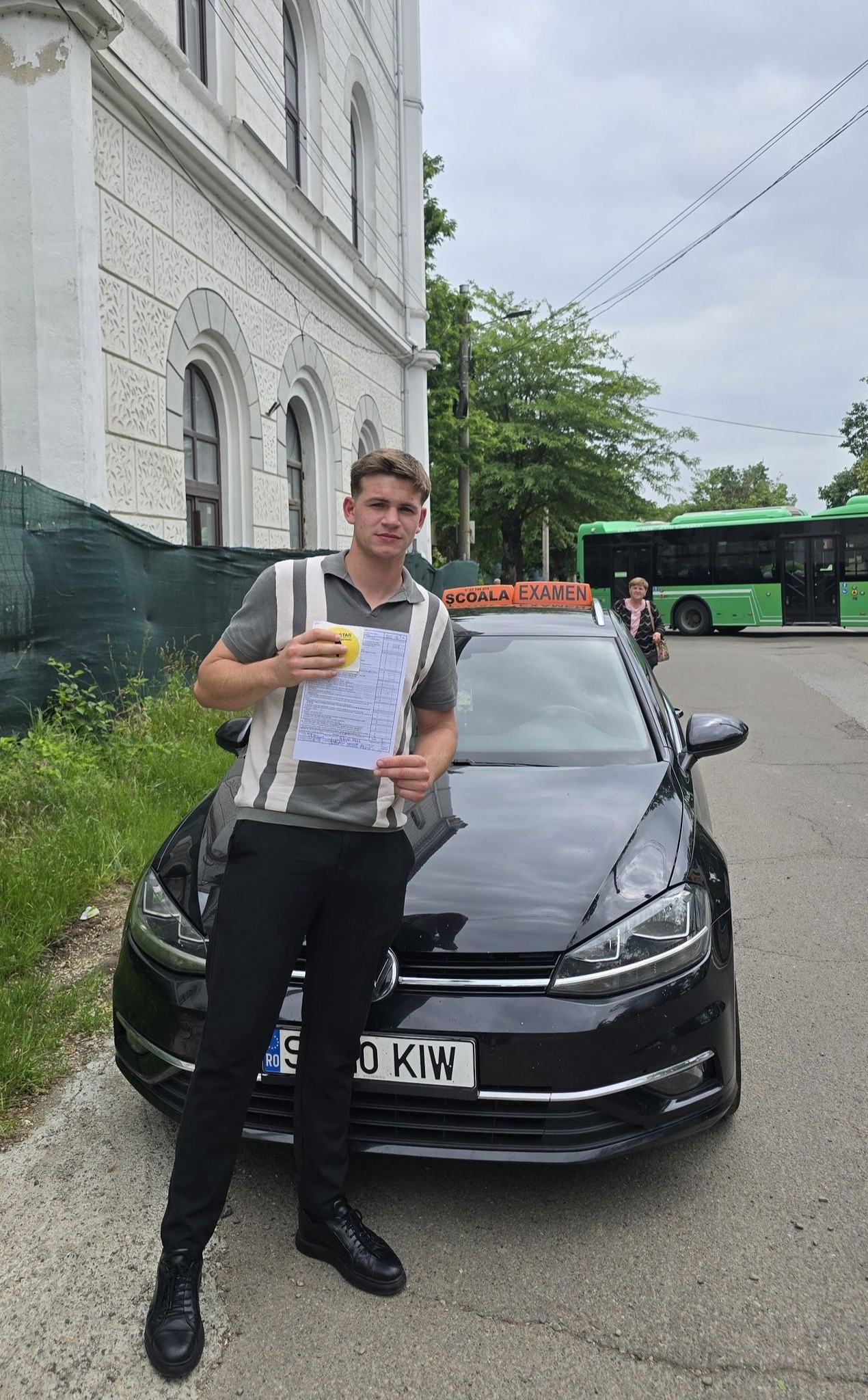 Absolvent AutoStar Drive lângă mașina de școală după examen