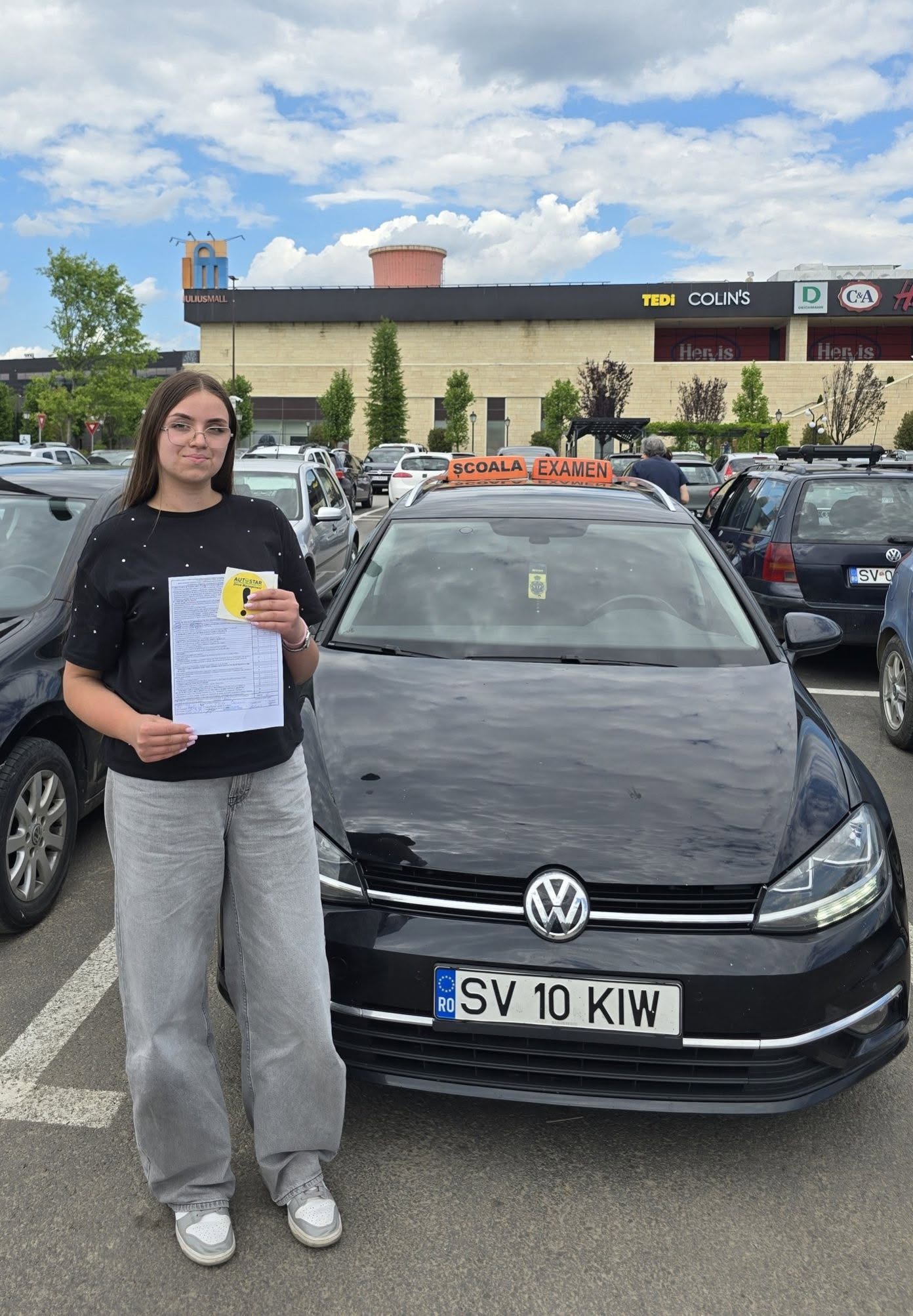 Absolventă AutoStar Drive lângă mașina de școală după examen